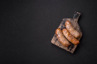 Koyu beton arka planda fırında tavuk ya da domuz sosisi, tuz, baharat ve otlar.