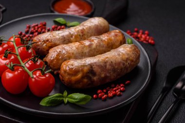 Koyu beton arka planda fırında tavuk ya da domuz sosisi, tuz, baharat ve otlar.