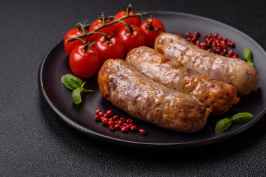 Koyu beton arka planda fırında tavuk ya da domuz sosisi, tuz, baharat ve otlar.