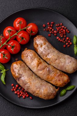 Koyu beton arka planda fırında tavuk ya da domuz sosisi, tuz, baharat ve otlar.