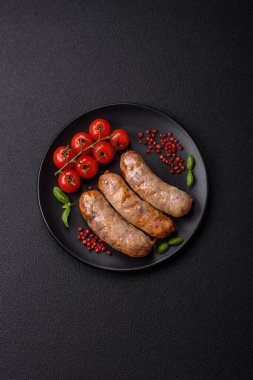 Koyu beton arka planda fırında tavuk ya da domuz sosisi, tuz, baharat ve otlar.