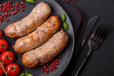 Koyu beton arka planda fırında tavuk ya da domuz sosisi, tuz, baharat ve otlar.