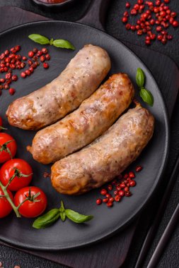 Koyu beton arka planda fırında tavuk ya da domuz sosisi, tuz, baharat ve otlar.