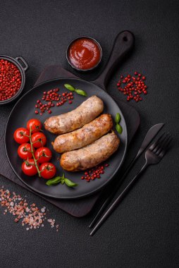 Koyu beton arka planda fırında tavuk ya da domuz sosisi, tuz, baharat ve otlar.