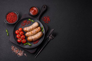 Koyu beton arka planda fırında tavuk ya da domuz sosisi, tuz, baharat ve otlar.