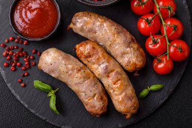 Koyu beton arka planda fırında tavuk ya da domuz sosisi, tuz, baharat ve otlar.