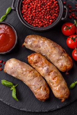 Koyu beton arka planda fırında tavuk ya da domuz sosisi, tuz, baharat ve otlar.