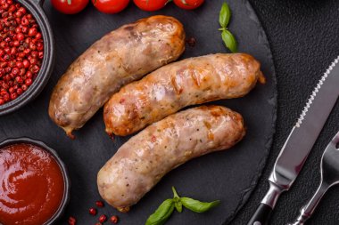 Koyu beton arka planda fırında tavuk ya da domuz sosisi, tuz, baharat ve otlar.