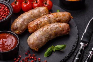 Koyu beton arka planda fırında tavuk ya da domuz sosisi, tuz, baharat ve otlar.