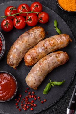 Koyu beton arka planda fırında tavuk ya da domuz sosisi, tuz, baharat ve otlar.