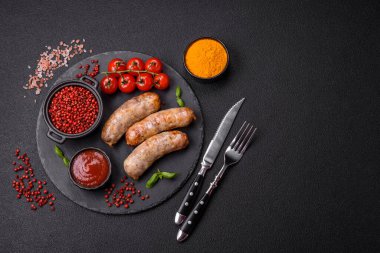 Koyu beton arka planda fırında tavuk ya da domuz sosisi, tuz, baharat ve otlar.