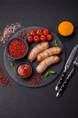 Koyu beton arka planda fırında tavuk ya da domuz sosisi, tuz, baharat ve otlar.