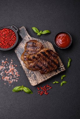 Karanlık bir arka planda taze sulu lezzetli biftek. Baharatlı ve otlu et yemeği.