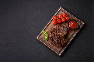 Karanlık bir arka planda taze sulu lezzetli biftek. Baharatlı ve otlu et yemeği.