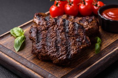 Karanlık bir arka planda taze sulu lezzetli biftek. Baharatlı ve otlu et yemeği.