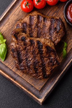 Karanlık bir arka planda taze sulu lezzetli biftek. Baharatlı ve otlu et yemeği.