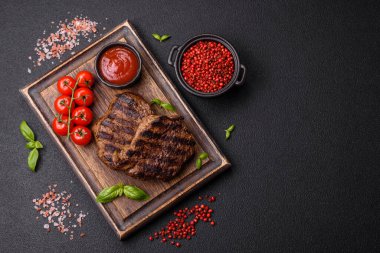 Karanlık bir arka planda taze sulu lezzetli biftek. Baharatlı ve otlu et yemeği.