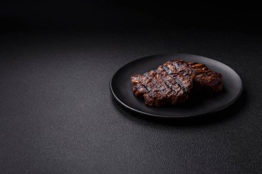 Karanlık bir arka planda taze sulu lezzetli biftek. Baharatlı ve otlu et yemeği.