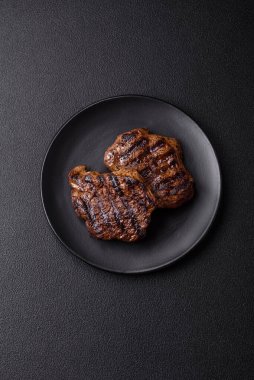 Karanlık bir arka planda taze sulu lezzetli biftek. Baharatlı ve otlu et yemeği.