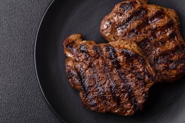 Karanlık bir arka planda taze sulu lezzetli biftek. Baharatlı ve otlu et yemeği.