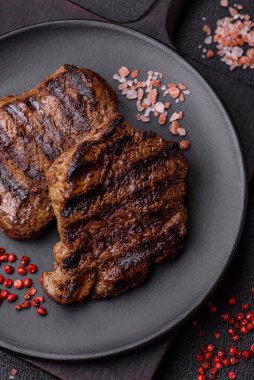 Karanlık bir arka planda taze sulu lezzetli biftek. Baharatlı ve otlu et yemeği.