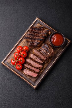 Karanlık bir arka planda taze sulu lezzetli biftek. Baharatlı ve otlu et yemeği.