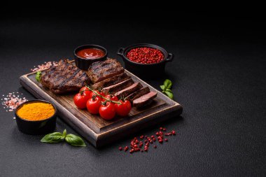 Karanlık bir arka planda taze sulu lezzetli biftek. Baharatlı ve otlu et yemeği.