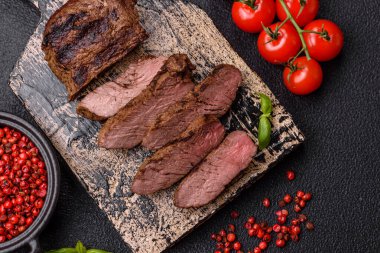 Karanlık bir arka planda taze sulu lezzetli biftek. Baharatlı ve otlu et yemeği.