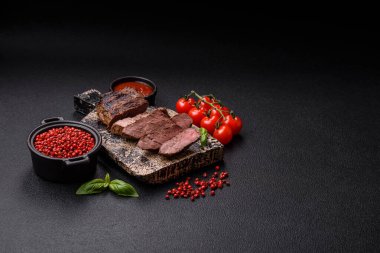 Karanlık bir arka planda taze sulu lezzetli biftek. Baharatlı ve otlu et yemeği.