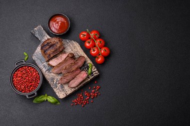 Karanlık bir arka planda taze sulu lezzetli biftek. Baharatlı ve otlu et yemeği.