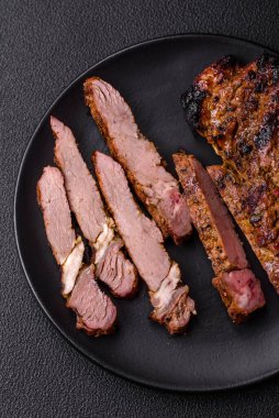 Izgarada pişirilmiş kemiğin üzerinde sulu etli baltalı biftek ve koyu beton arka planda tuz ve baharatlar.