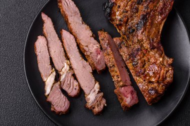 Izgarada pişirilmiş kemiğin üzerinde sulu etli baltalı biftek ve koyu beton arka planda tuz ve baharatlar.