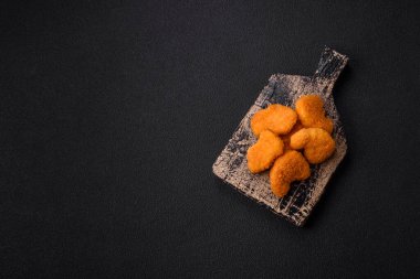 Delicious fresh crispy chicken nuggets on a dark concrete background. Unhealthy food, fast food