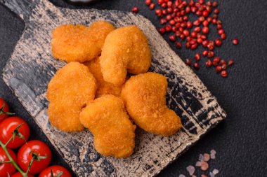 Delicious fresh crispy chicken nuggets on a dark concrete background. Unhealthy food, fast food