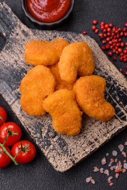 Delicious fresh crispy chicken nuggets on a dark concrete background. Unhealthy food, fast food