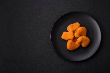 Delicious fresh crispy chicken nuggets on a dark concrete background. Unhealthy food, fast food