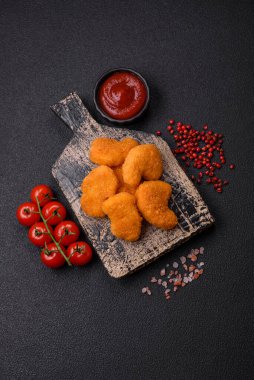 Delicious fresh crispy chicken nuggets on a dark concrete background. Unhealthy food, fast food