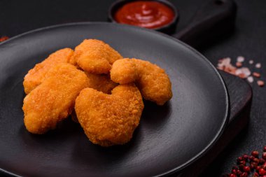 Delicious fresh crispy chicken nuggets on a dark concrete background. Unhealthy food, fast food