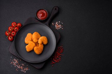 Delicious fresh crispy chicken nuggets on a dark concrete background. Unhealthy food, fast food