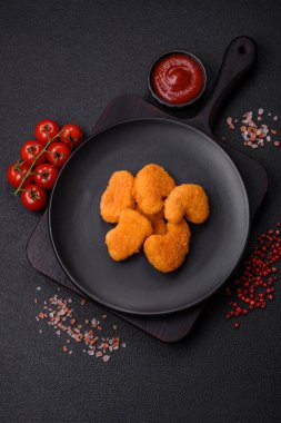 Delicious fresh crispy chicken nuggets on a dark concrete background. Unhealthy food, fast food