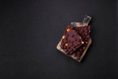 Fındıklı siyah acı çikolata, şekerli meyve ve nane. Koyu beton bir arka planda parçalara ayrılmış.