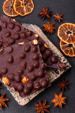 Fındıklı siyah acı çikolata, şekerli meyve ve nane. Koyu beton bir arka planda parçalara ayrılmış.