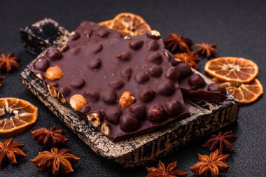 Fındıklı siyah acı çikolata, şekerli meyve ve nane. Koyu beton bir arka planda parçalara ayrılmış.
