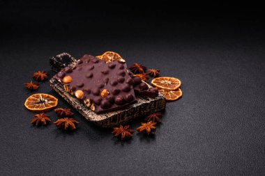 Fındıklı siyah acı çikolata, şekerli meyve ve nane. Koyu beton bir arka planda parçalara ayrılmış.