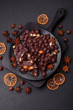 Fındıklı siyah acı çikolata, şekerli meyve ve nane. Koyu beton bir arka planda parçalara ayrılmış.