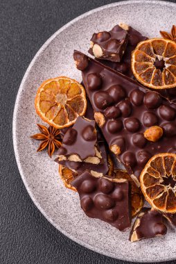 Fındıklı siyah acı çikolata, şekerli meyve ve nane. Koyu beton bir arka planda parçalara ayrılmış.