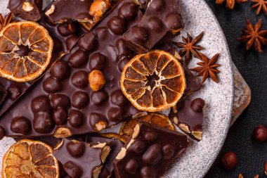 Fındıklı siyah acı çikolata, şekerli meyve ve nane. Koyu beton bir arka planda parçalara ayrılmış.