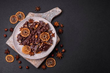 Fındıklı siyah acı çikolata, şekerli meyve ve nane. Koyu beton bir arka planda parçalara ayrılmış.