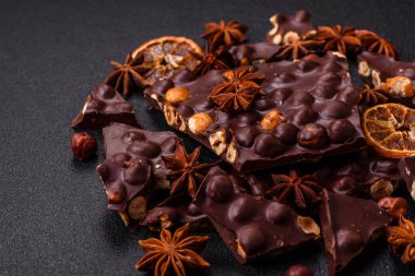 Fındıklı siyah acı çikolata, şekerli meyve ve nane. Koyu beton bir arka planda parçalara ayrılmış.