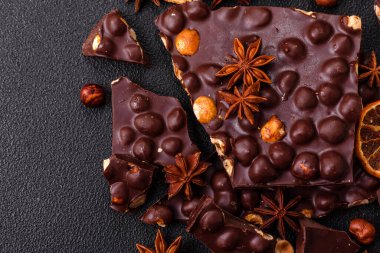 Fındıklı siyah acı çikolata, şekerli meyve ve nane. Koyu beton bir arka planda parçalara ayrılmış.